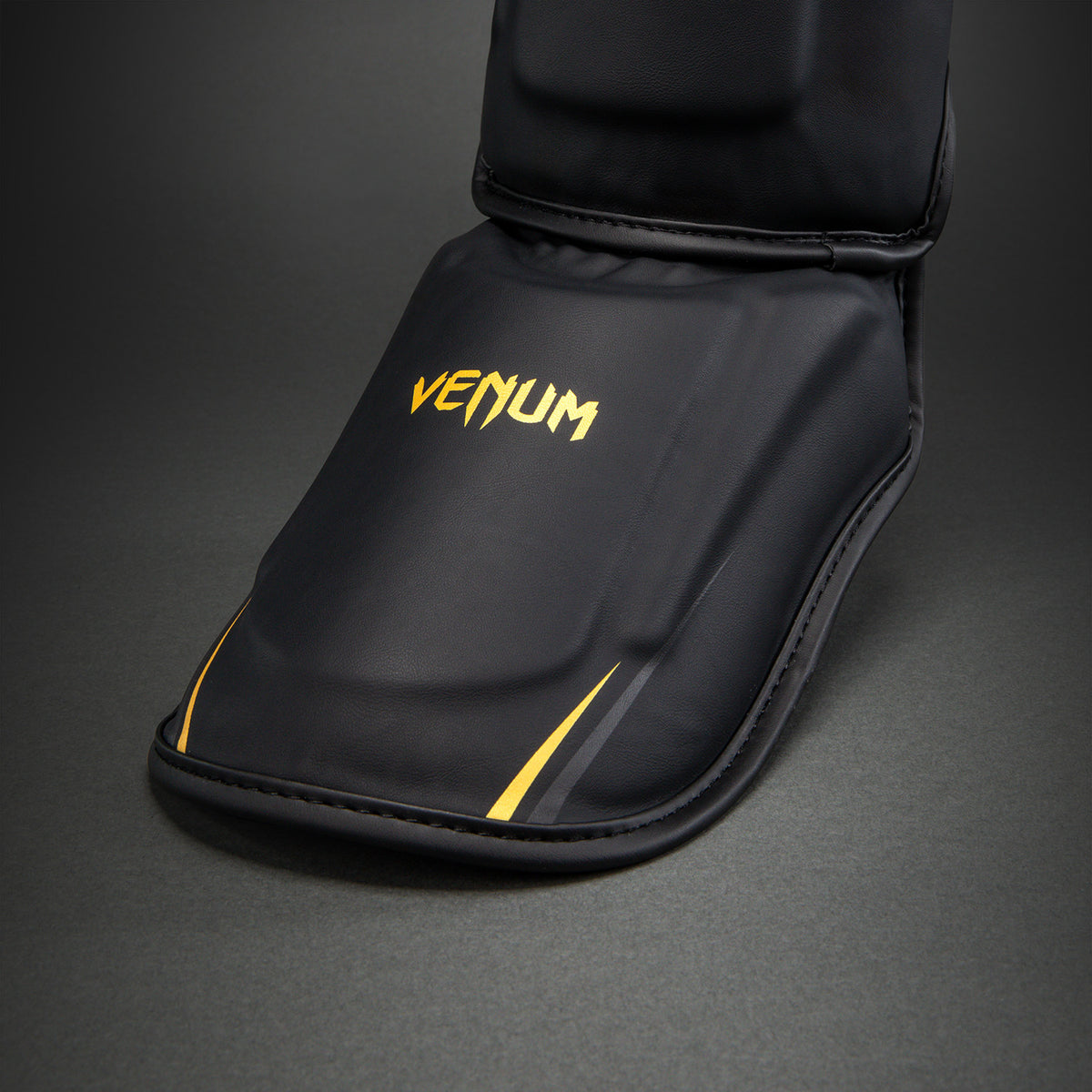 Venum G-Core Espinilleras - Negro/Oro